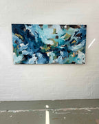 Abstract painting with blue and white tones on a white brick wall.