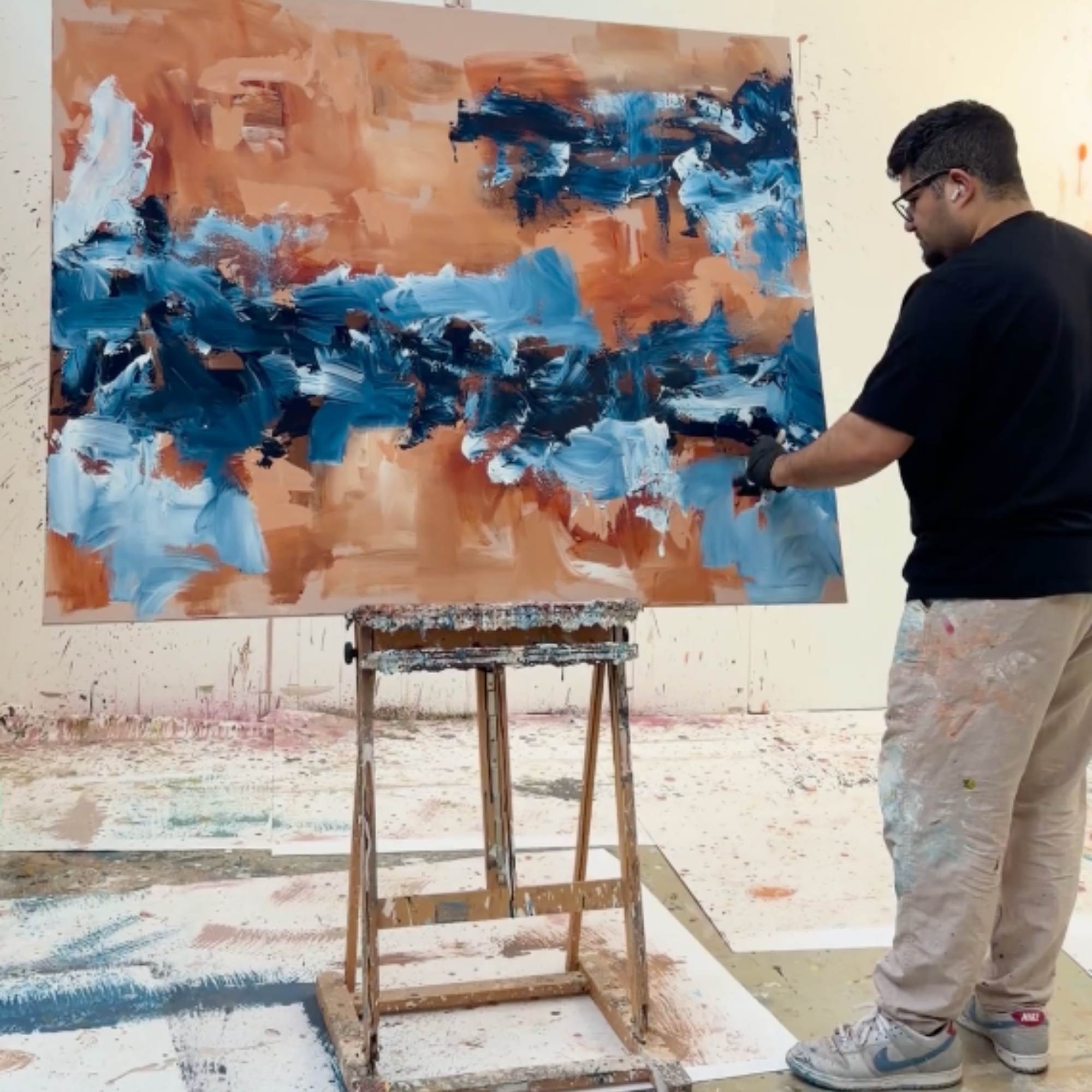 Artist Omar Obaid working on a large abstract painting in an art studio.