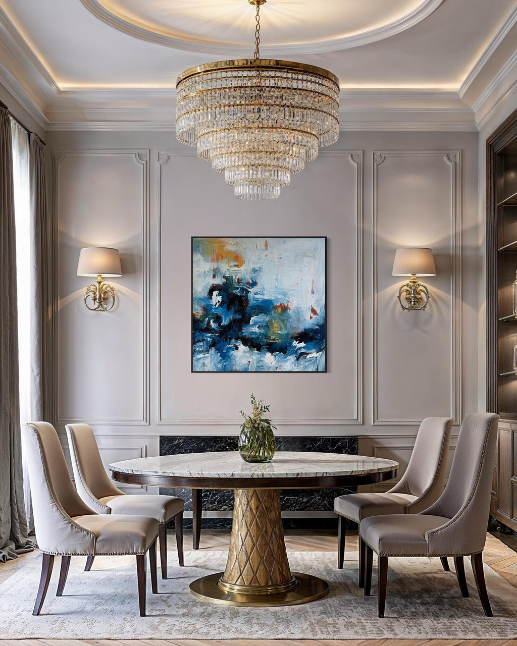 Elegant dining room with a round marble table, gold chandelier, and abstract art on the wall.