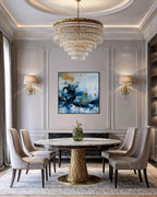 Elegant dining room with a round marble table, gold chandelier, and abstract art on the wall.