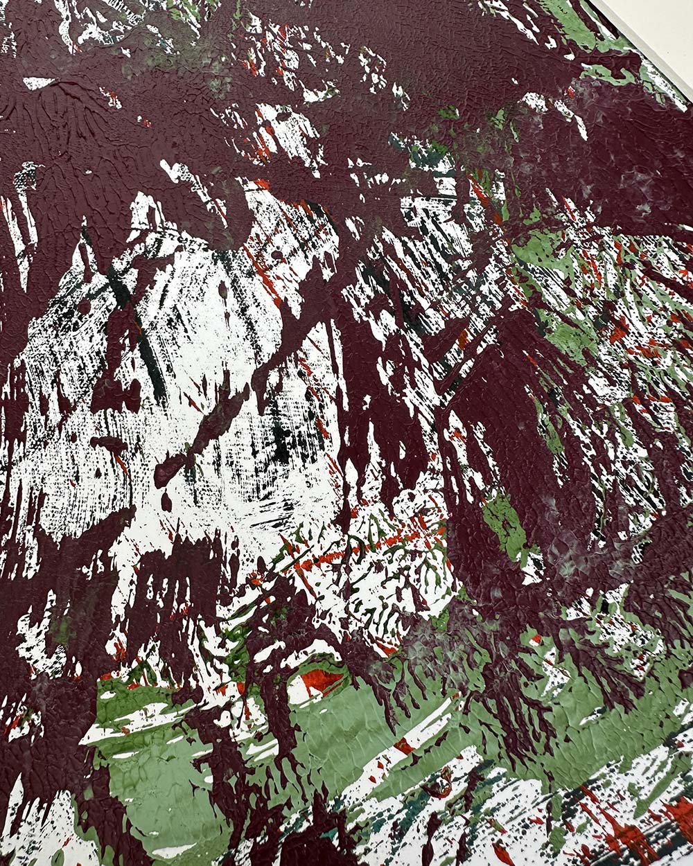 Abstract art with splashes of red, green, and black on a textured surface